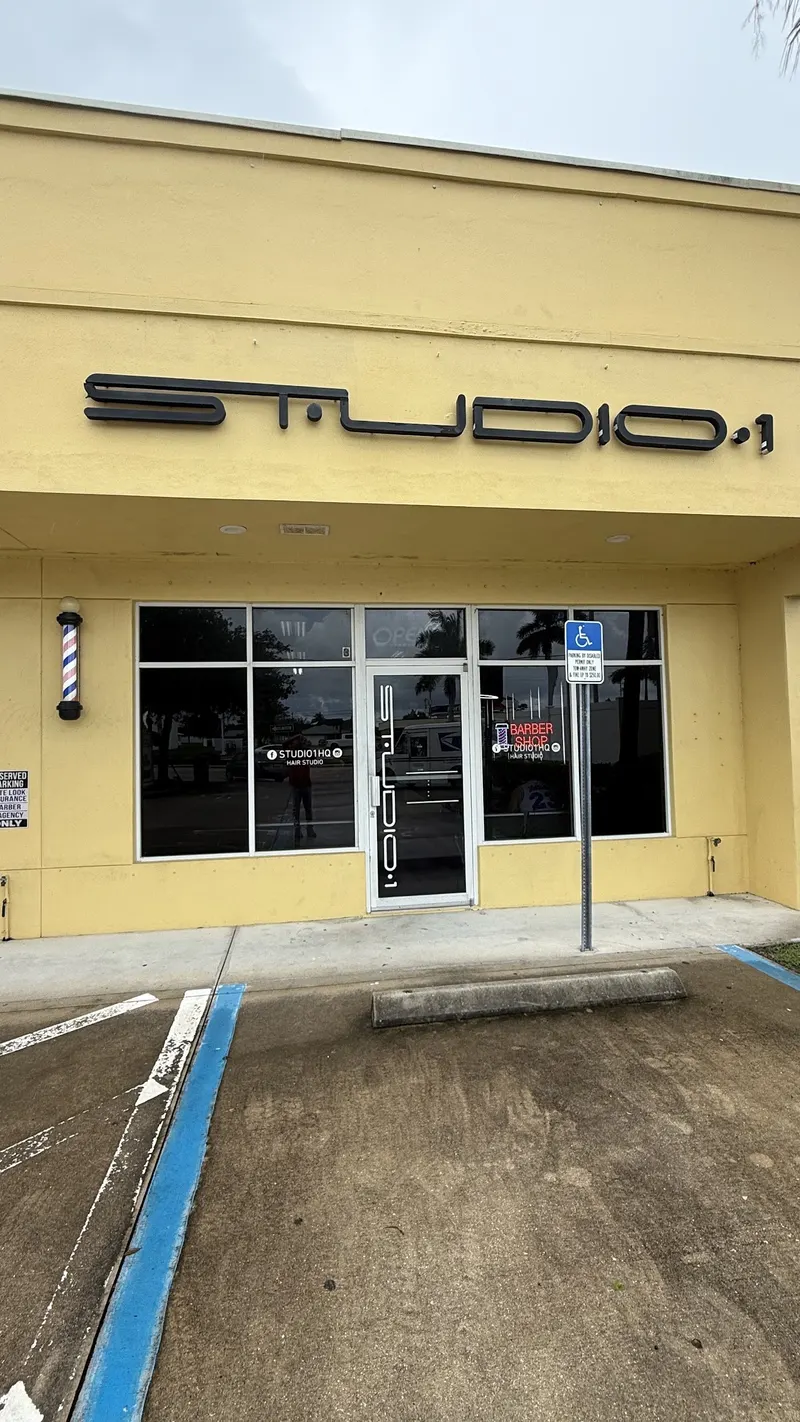 Front of the plaza where Enzo Barbershop is, yellow building with a blue accessible parking space